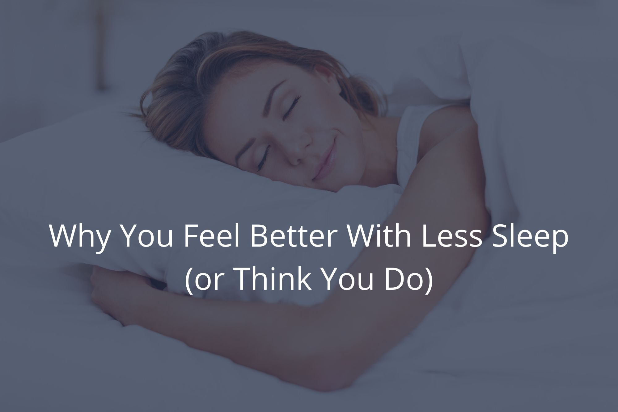 A woman smiles as she lies in a white bed with her eyes closed, realizing you don’t really feel better with less sleep.