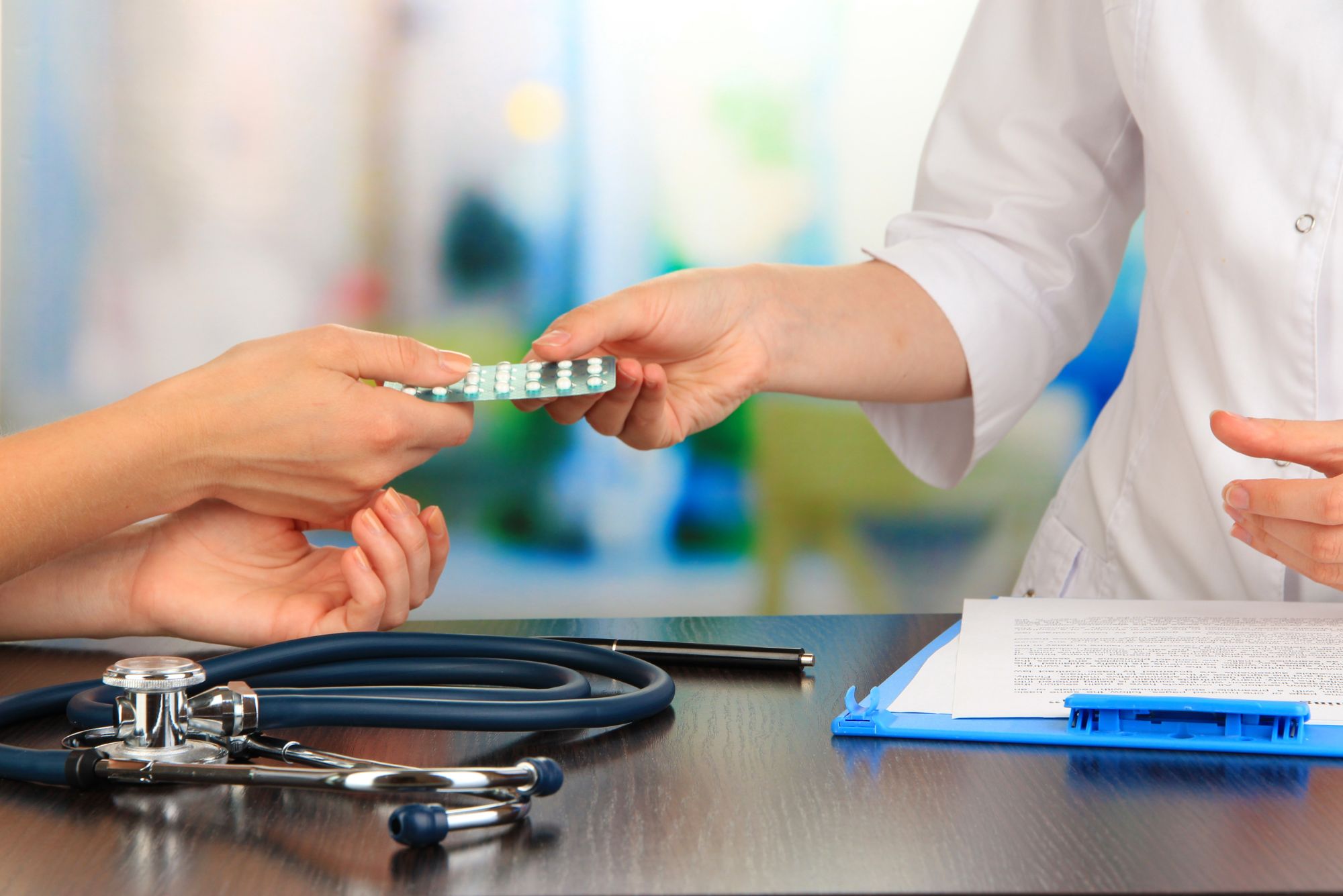 A doctor who noticed the signs that a patient needs hormone replacement therapy hands a packet of pills to a female patient.