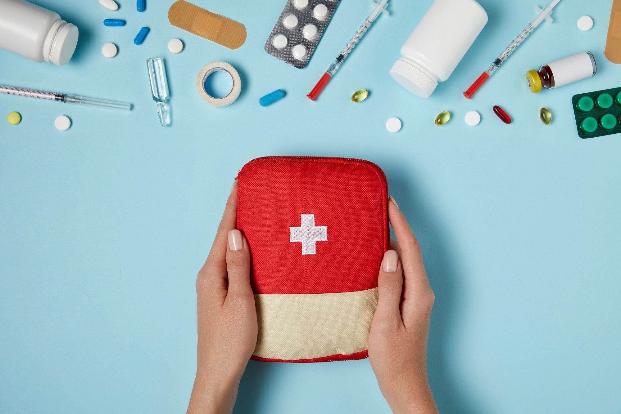 A woman holding a first aid kit figuring out what to pack in your travel medicine bag.