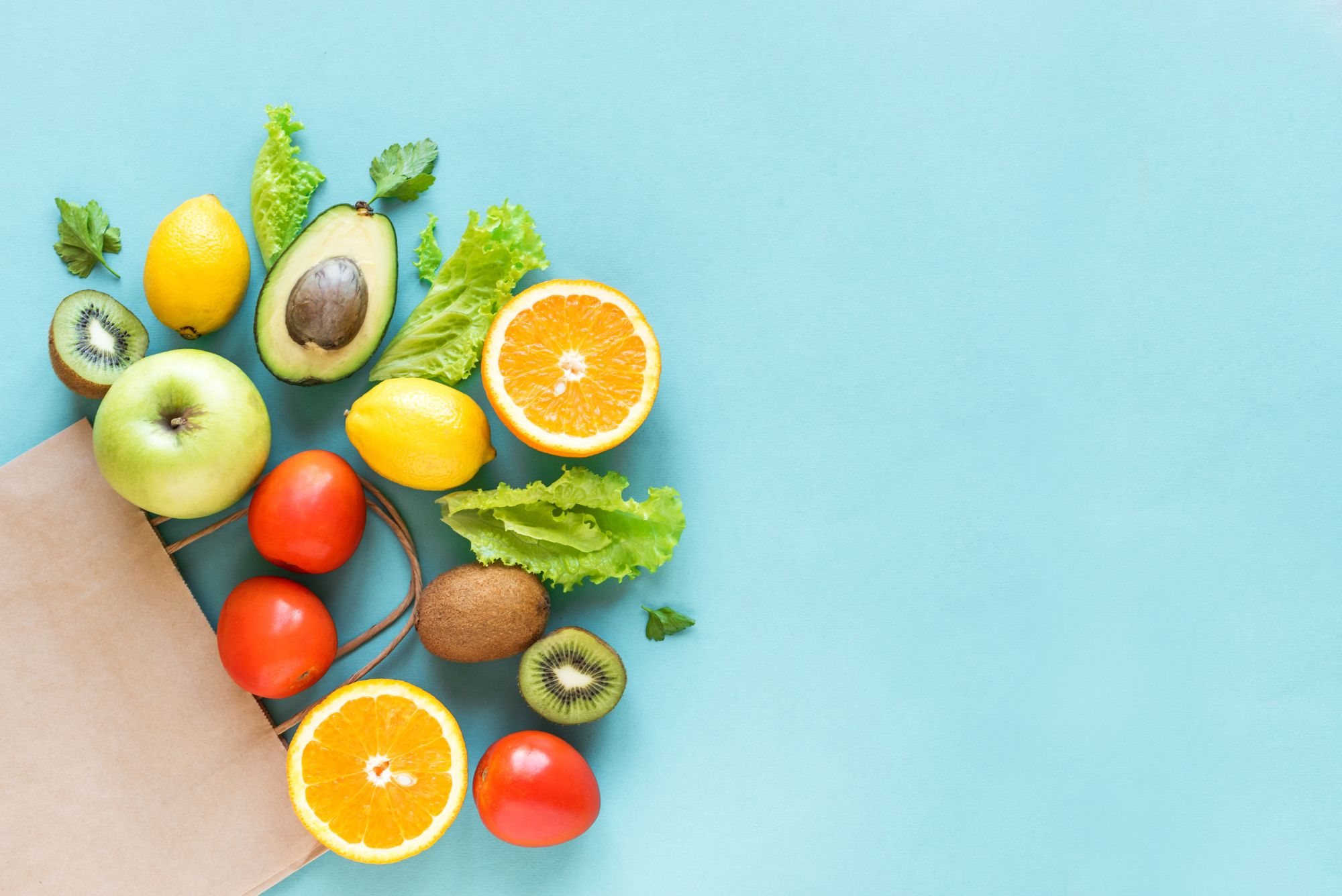 A grocery bag laying on a blue table after someone learned how to grocery shop healthy.