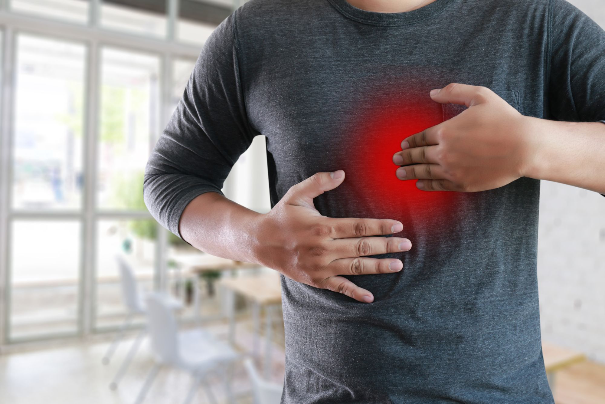 A man with reflux pain massages his chest while wondering how long acid reflux takes to heal.