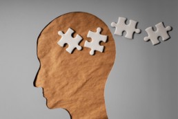 A brown paper cut-out of someone’s head with 4 white puzzle pieces floating out of it represents common myths about dementia.