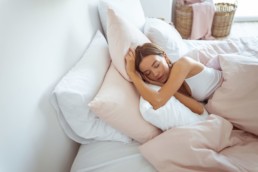 A woman asleep in her bed peacefully after improving her sleep hygiene.