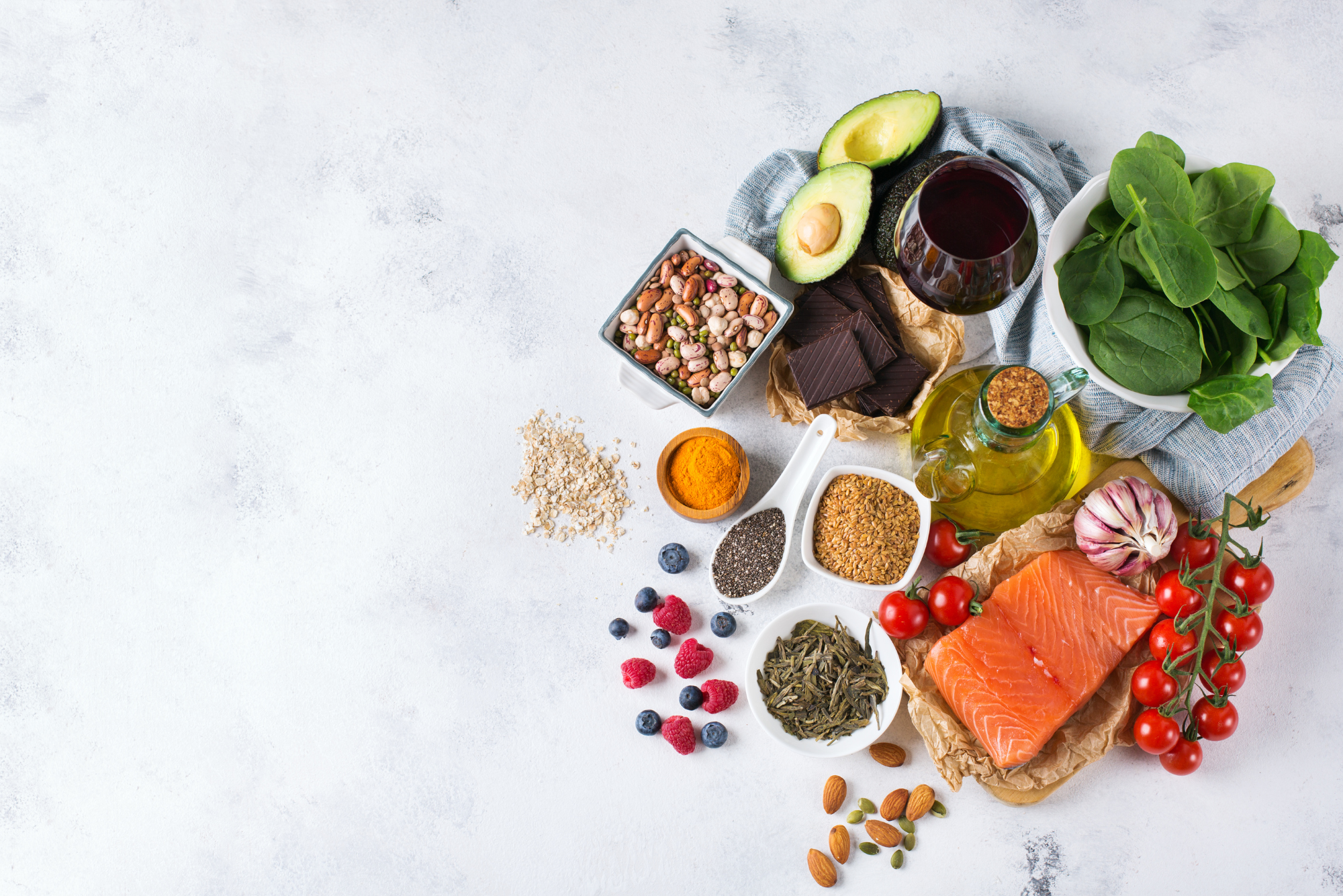 Various healthy foods that are good for people with high cholesterol are piled together on a marble countertop.