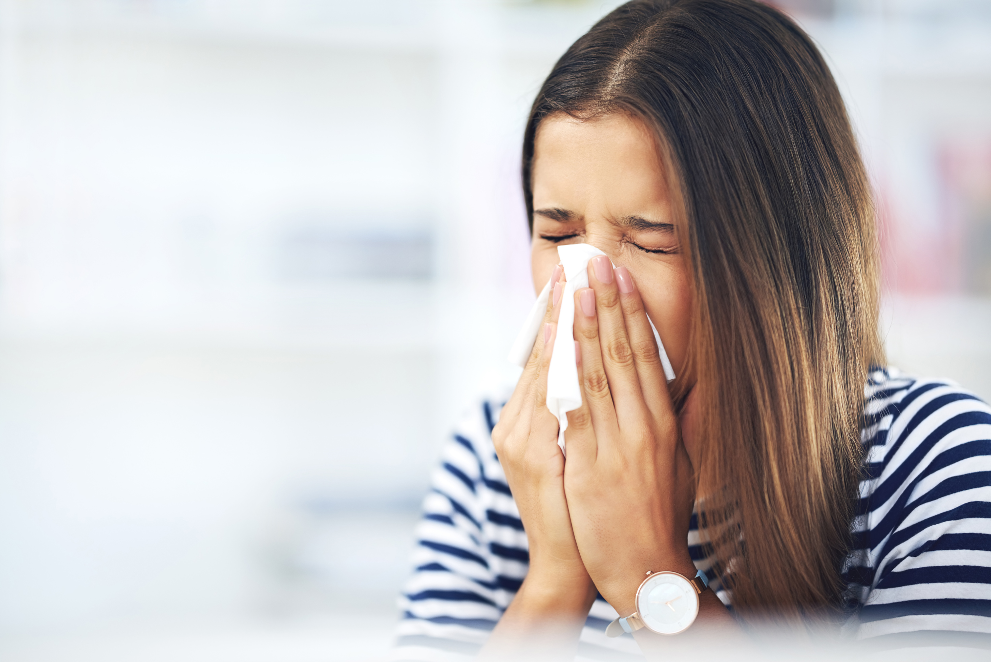 A woman in need of tips for seasonal allergies blows her nose into a tissue.