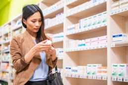 After learning how to read medication labels properly, a woman examines an OTC medicine in a drugstore aisle.