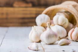 A bag of garlic, and immune-support food, on its side, overflowing with garlic cloves.