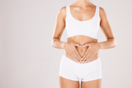 A woman holds her hands in the shape of a heart over her stomach, symbolizing how to heal your gut naturally.