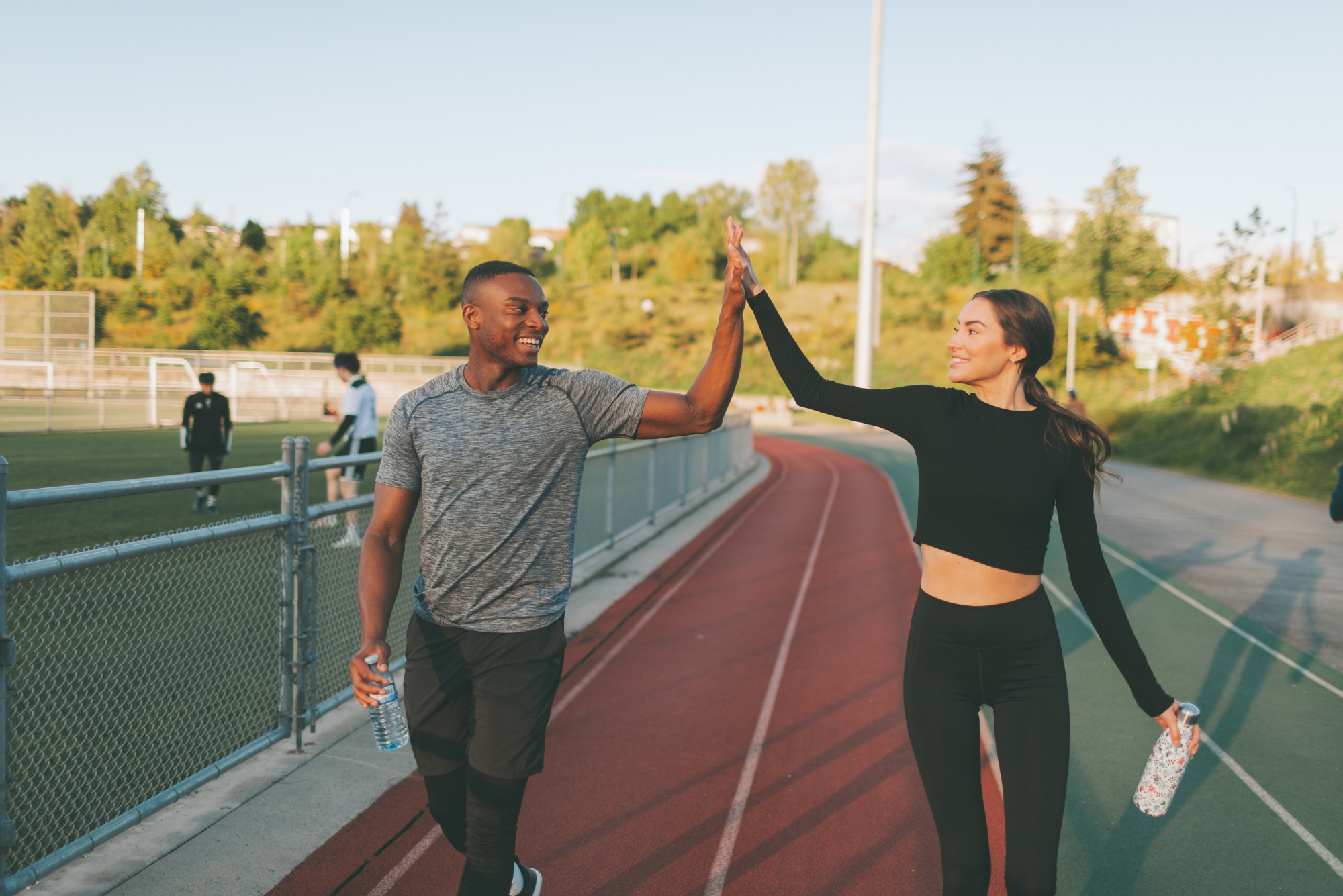 Two friends exchange smiles and a high-five, celebrating their completed workout, showing their commitment to the pillars of health.