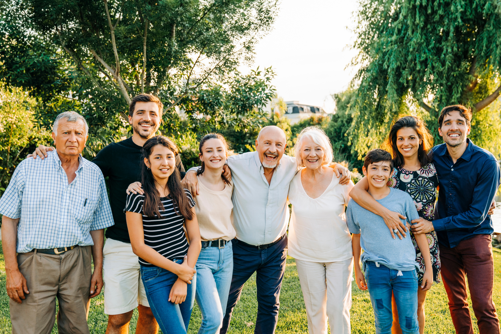 Multiple members of an extended family smile together in a family portrait because being with family gives them happiness.