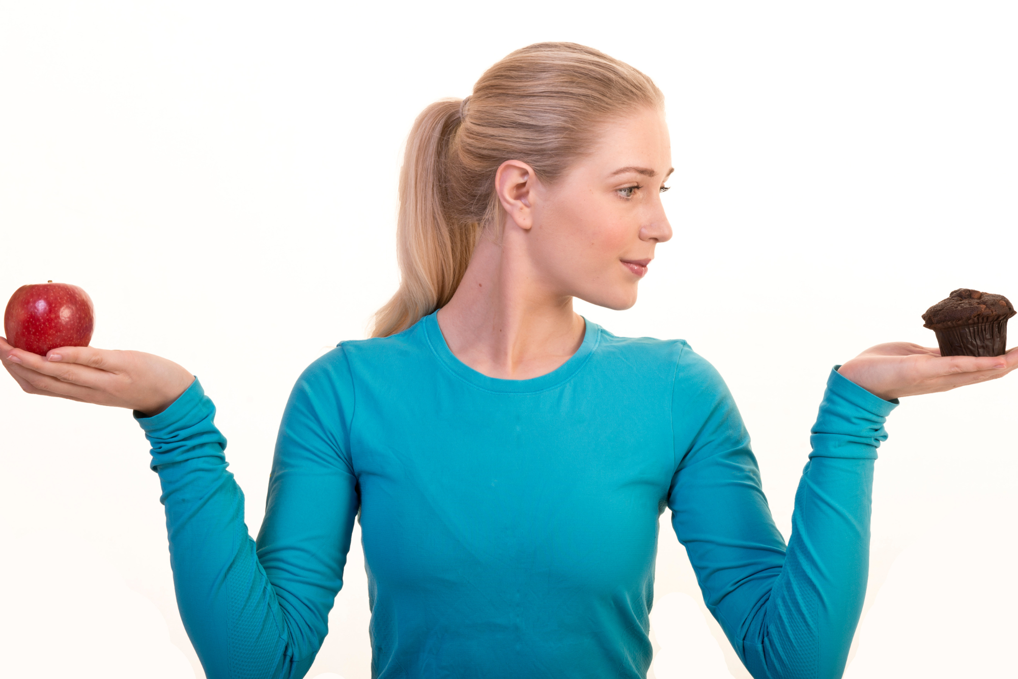 A woman in a blue long sleeve shirt holds an apple in one hand, and a cupcake in the other, representing making healthy choices.