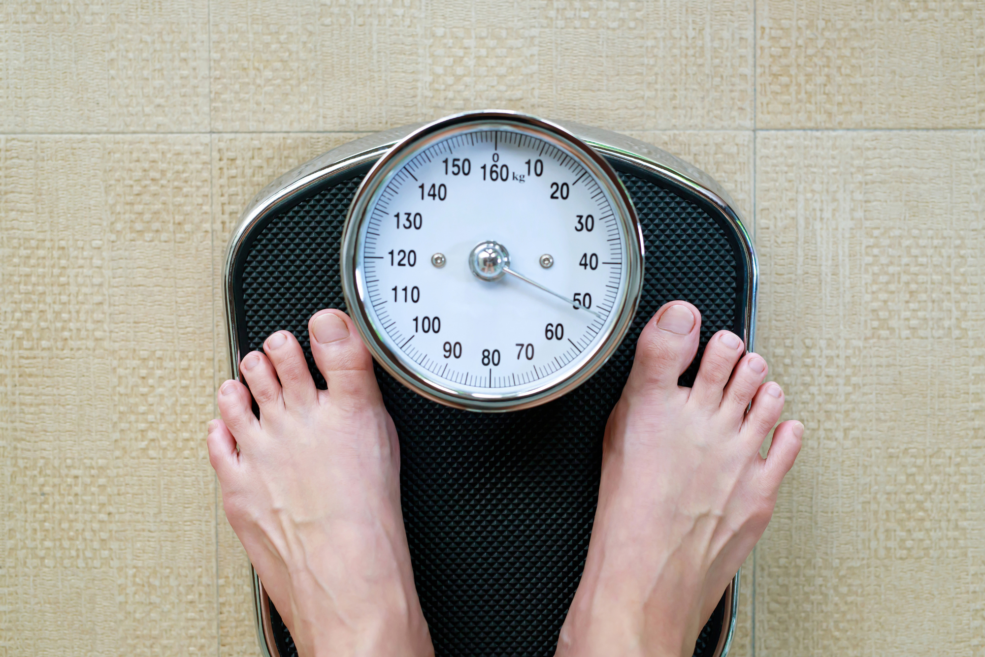 Bare feet on a scale, prompting the question: Does fat make you fat?