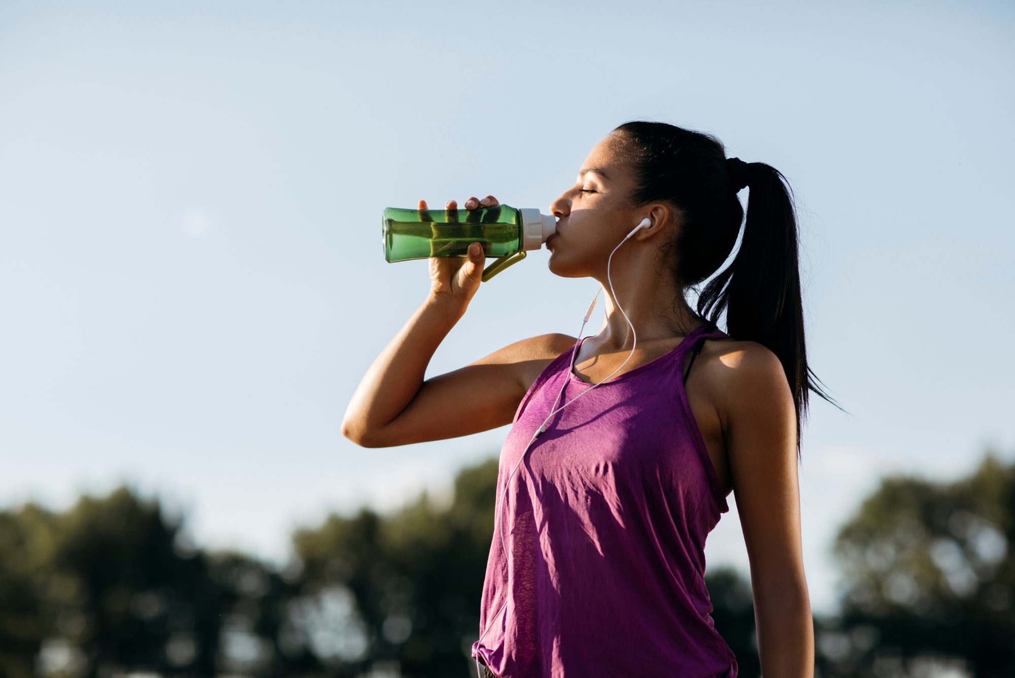 Young woman in athletic clothing drinking water from bottle after workout.
