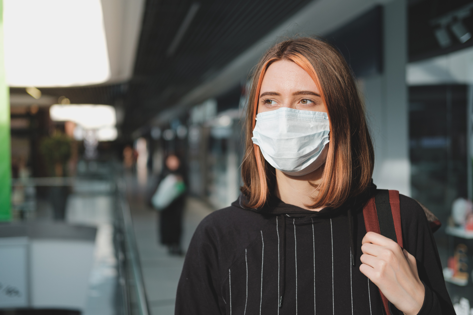 A woman wearing a mask while standing in a public place.