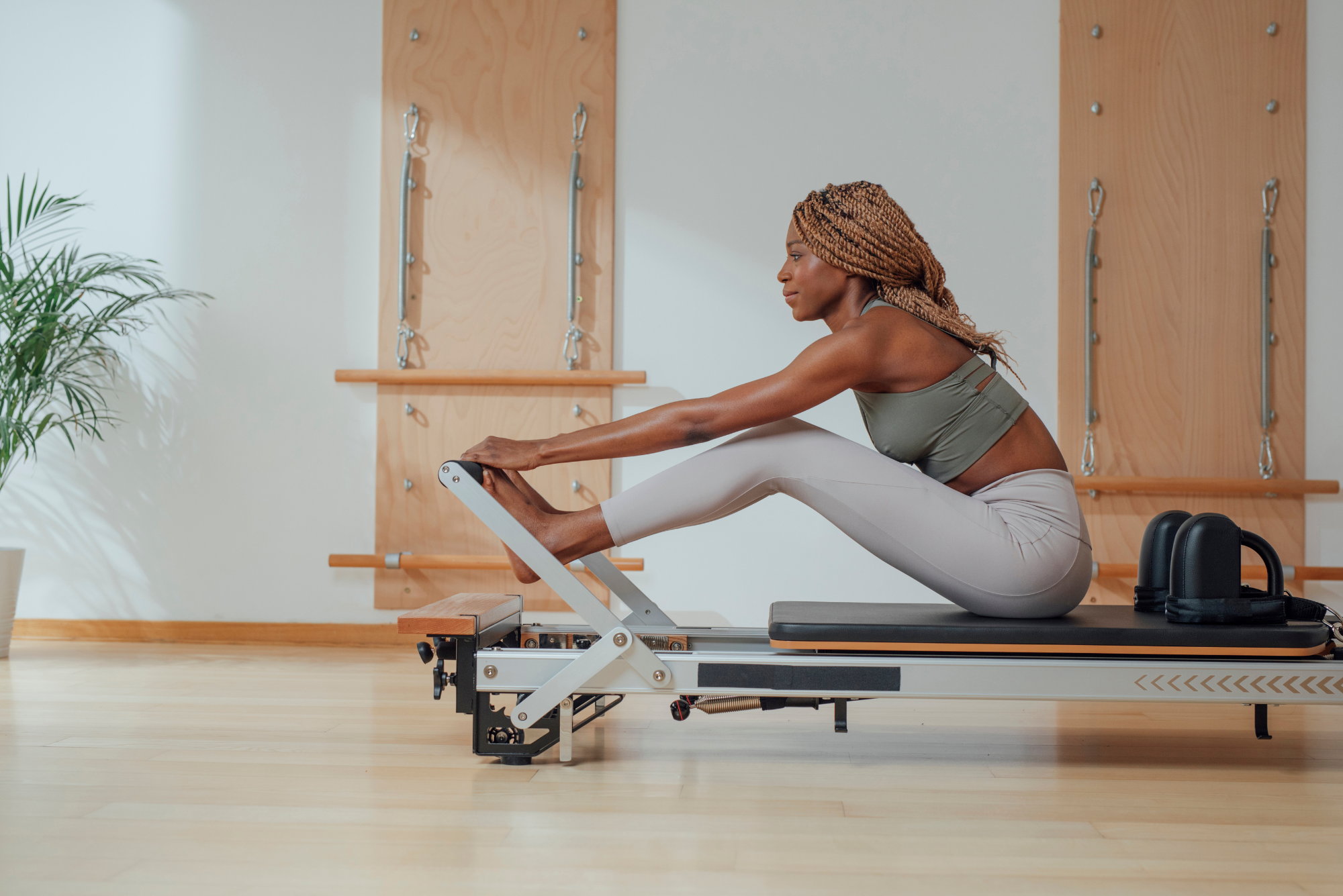 Woman performing a core exercise on a Pilates reformer machine.