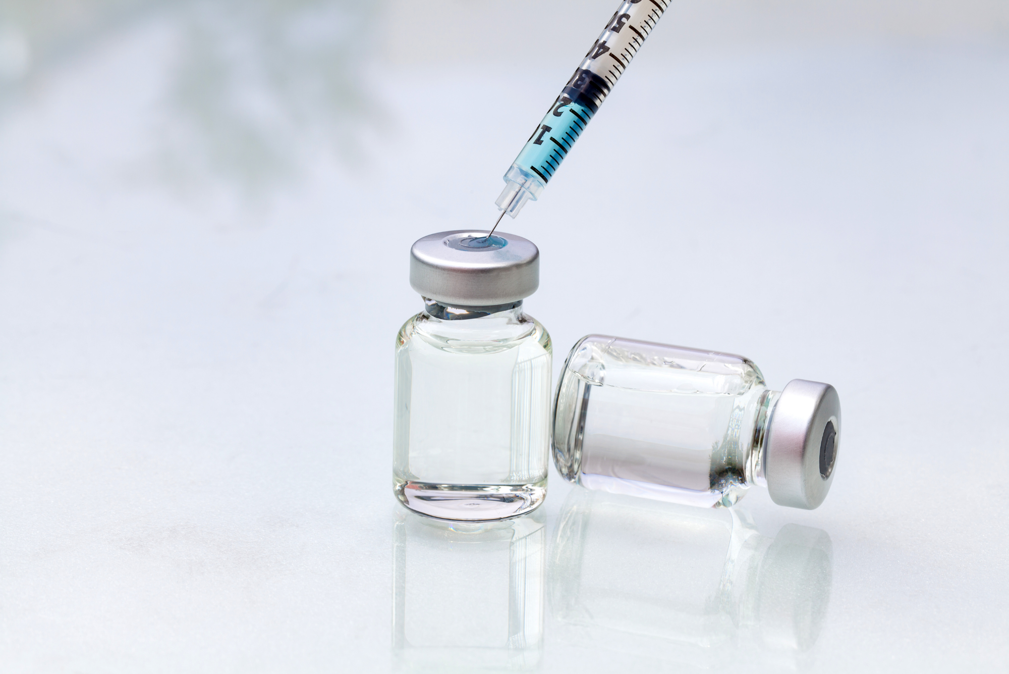 A syringe draws liquid from a glass medical vial, illustrating peptide therapy.